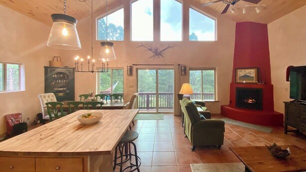 A spacious living area with a large wooden dining table, a fireplace, and a cozy seating arrangement. - Spacious Cabin-6 min to AF Resort, min to hiking,biking,restaurants,grocerystore (Angel Fire)