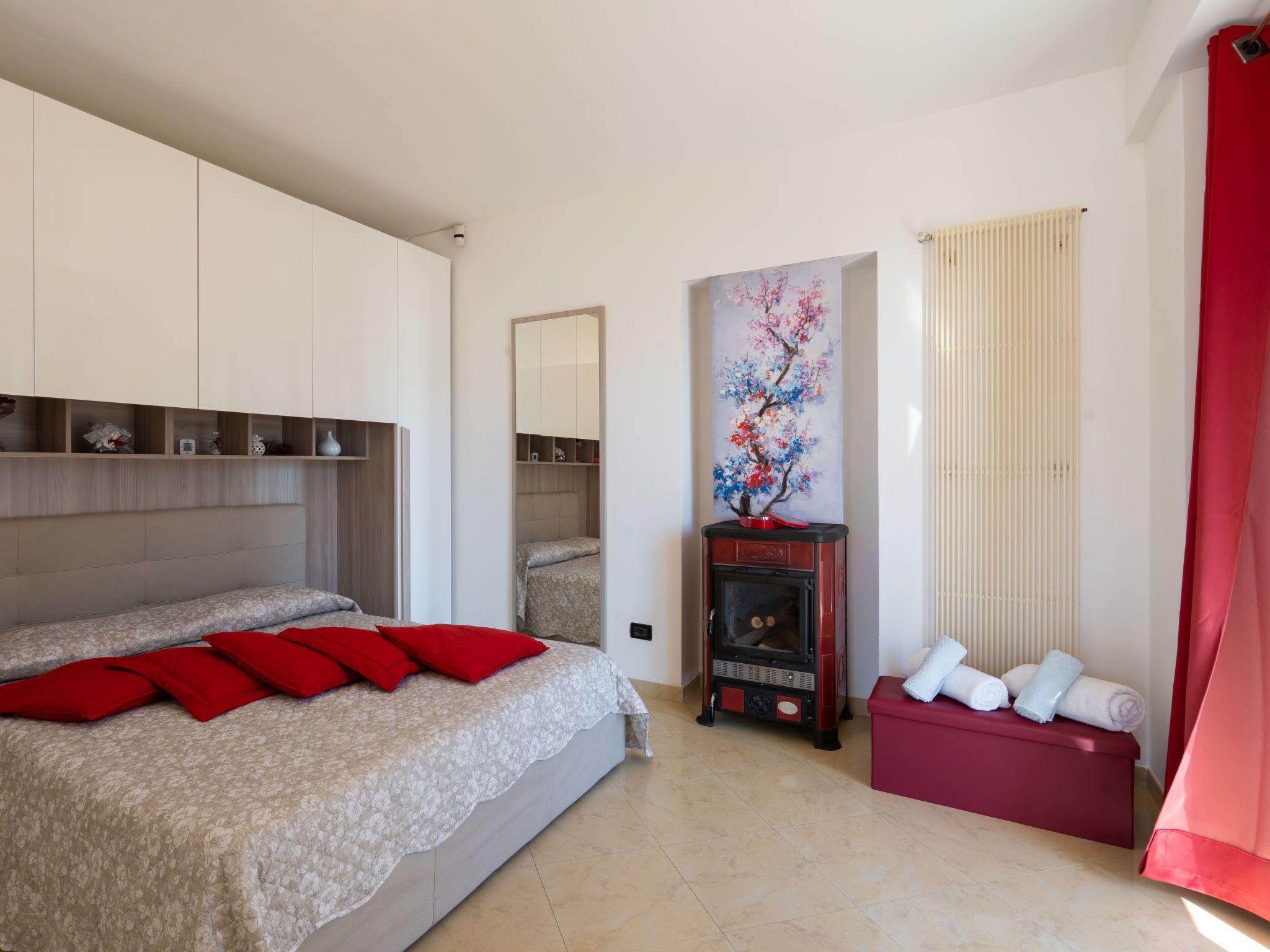 Een slaapkamer met een bed, een open haard, een rode bank en een schilderij aan de muur.
