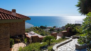 Una propiedad costera con un camino de piedra, vistas al mar y una casa de ladrillo con tejado de tejas.