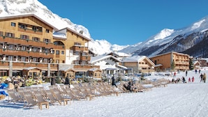 A hotel with multiple floors, outdoor seating, and a ski slope in the background.