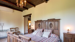 A bedroom with a wooden bed, a chandelier, a nightstand, and a mirror. - Marmorito by Interhome (Portacomaro)