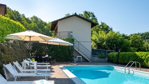 A swimming pool with lounge chairs and umbrellas, a staircase leading to a building, and a landscaped garden. - Marmorito by Interhome (Portacomaro)