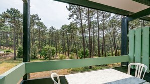 A covered outdoor seating area with a table and chairs, overlooking a forested landscape.