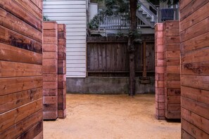 A wooden gate leading to a sandy area with a concrete wall and a wooden fence in the background.