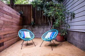 Eine Terrasse mit zwei blauen Stühlen und einem Blumentopf.