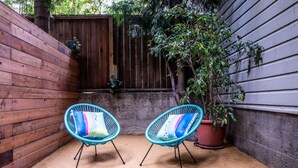 A small outdoor area with two turquoise chairs and a potted plant.