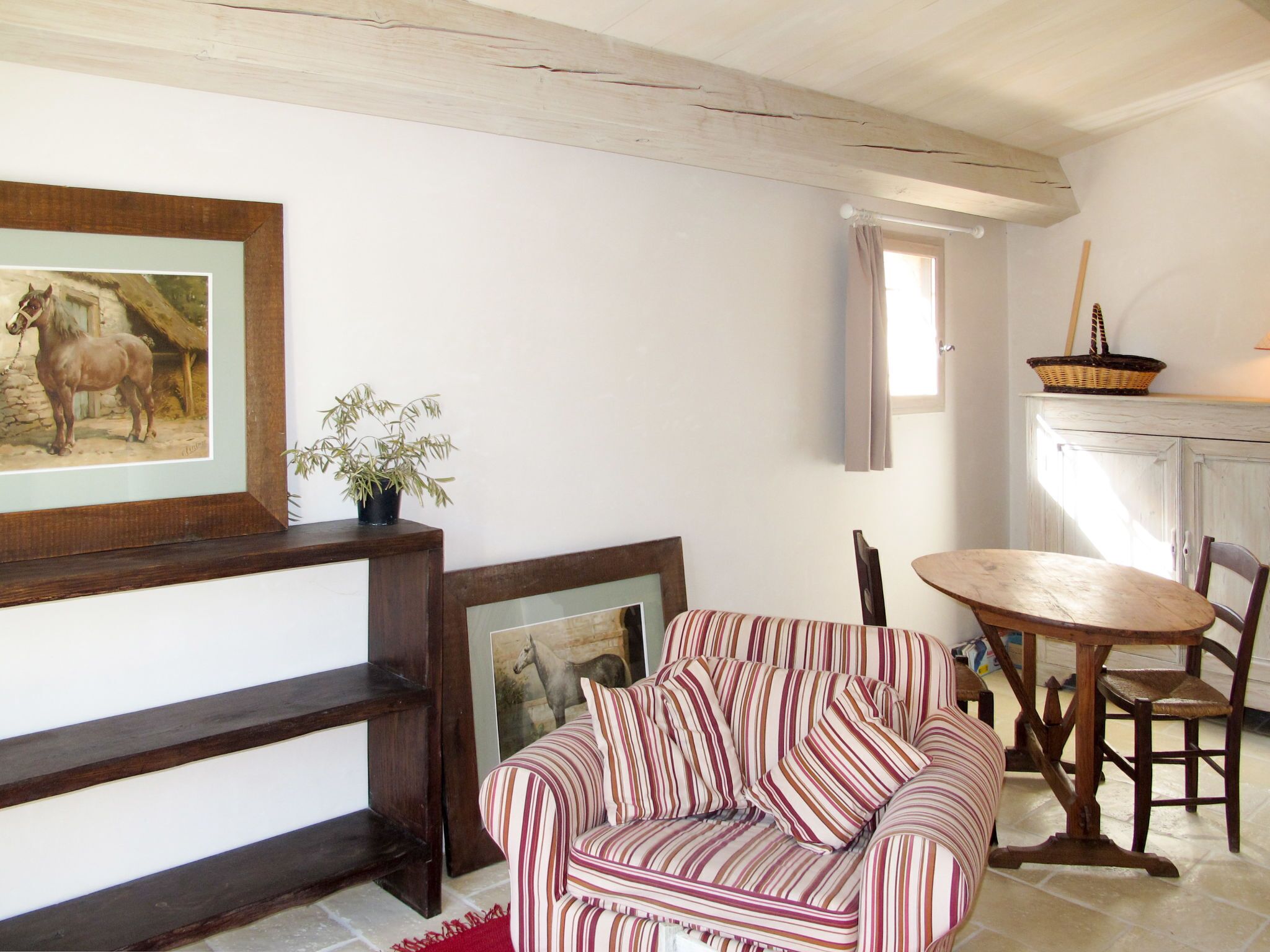 Uma sala de estar acolhedora com um sofá listrado, uma mesa de centro de madeira e um quadro de cavalos na parede.