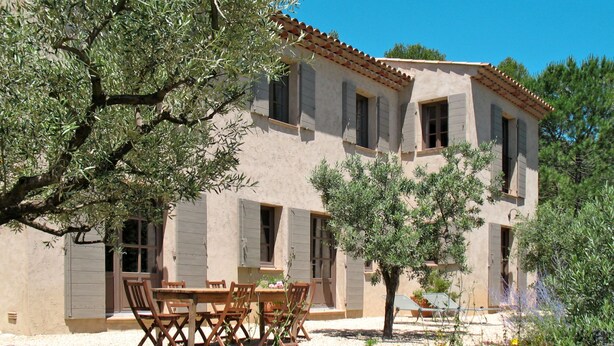 A two-story building with a tiled roof, multiple windows, and a patio area with a table and chairs. - Le Collet des Redons by Interhome (Lorgues)