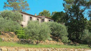 A poolside area with lounge chairs, a stone wall, and a building with a tiled roof. - Le Collet des Redons by Interhome (Lorgues)