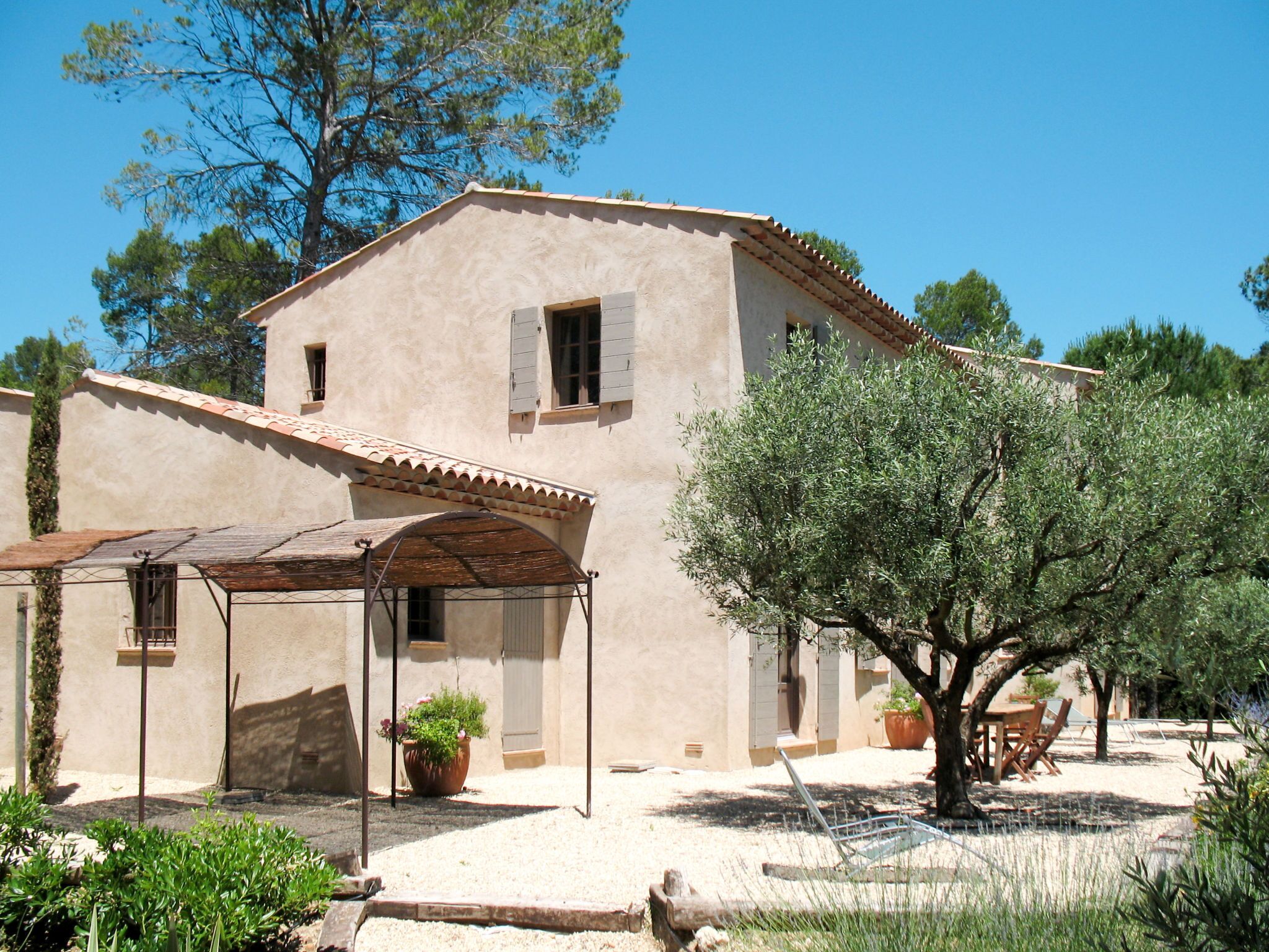 A two-story building with a tiled roof and a covered patio area.