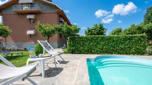 A poolside area with lounge chairs, a brick building, and a hedge in the background. - Ca' D'Gnese by Interhome (Castagnole Lanze)