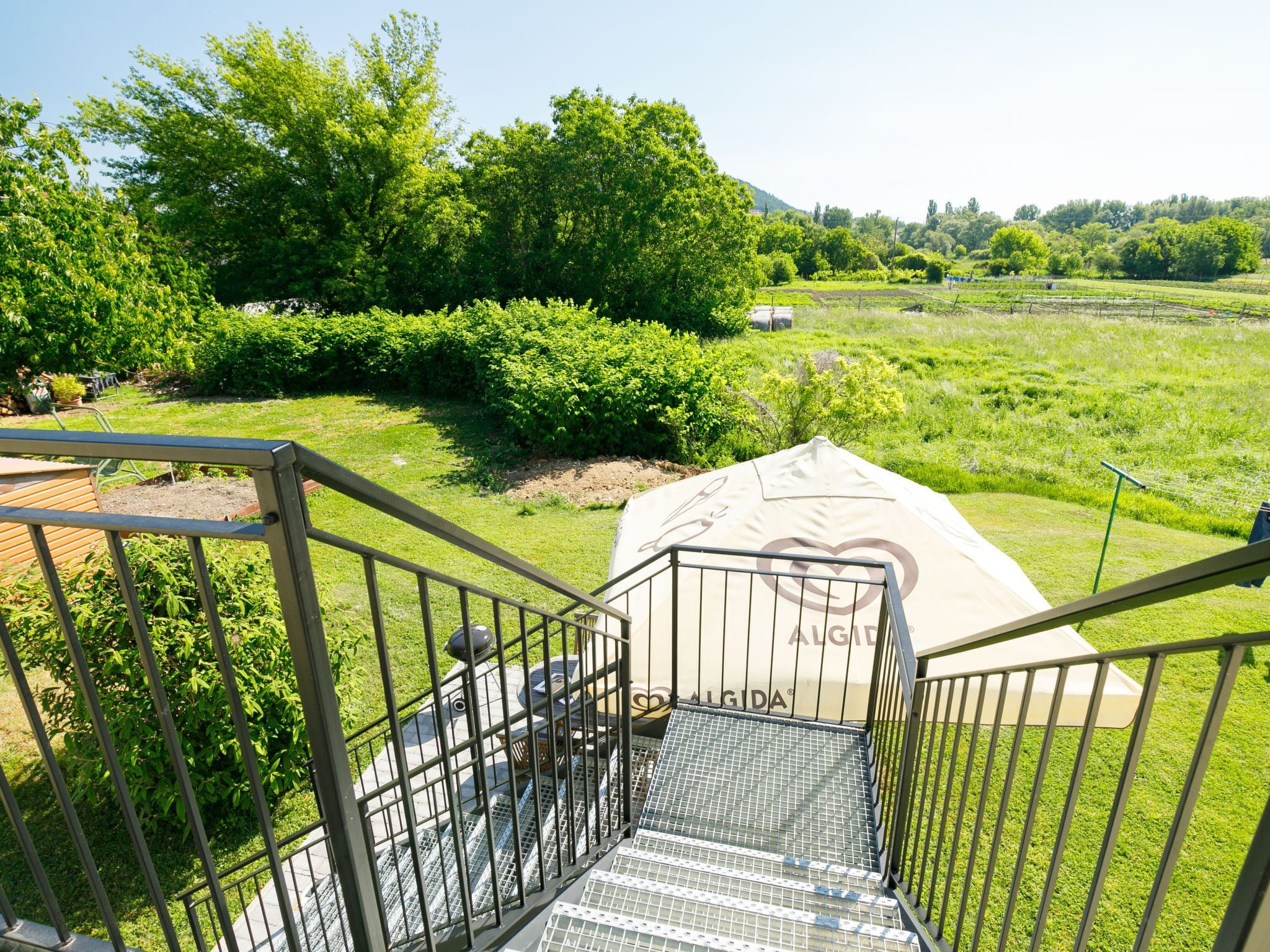 Eine Treppe führt zu einem überdachten Außenbereich mit Blick auf eine üppige, grüne Landschaft und Bäume.