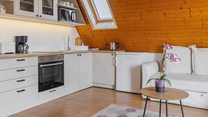 Een kleine keuken met een inbouwoven, koffiezetapparaat en koelkast.