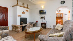 Uma sala de estar com lareira, televisão na parede e sofá.