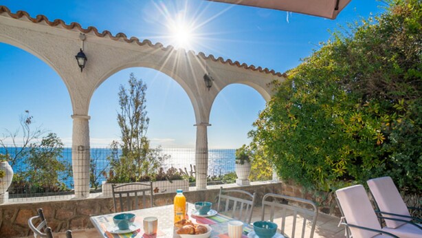 A sunlit patio with a table set for two, overlooking a coastal view. - La Rocade by Interhome (Théoule sur mer)