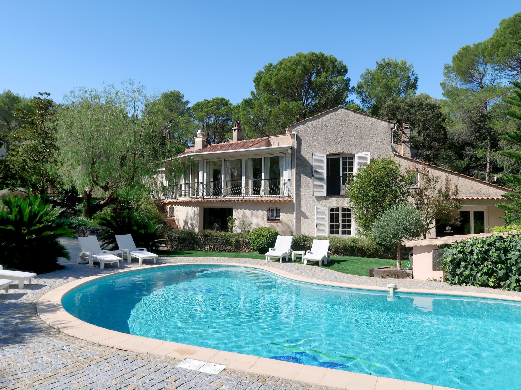 A large house with a swimming pool, surrounded by trees and greenery.