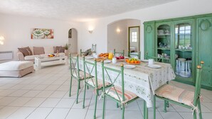 A dining area with a table set for four, surrounded by green chairs. There is a green cabinet with glass doors to the right. - Mas des Chênes by Interhome (Grimaud)