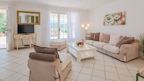 A living room with a sofa, a coffee table, a TV, and a painting on the wall. - Mas des Chênes by Interhome (Grimaud)