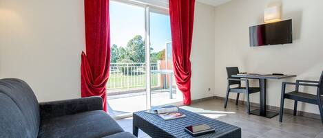 A modern living room with a sofa, a coffee table, and a dining area with chairs and a table.