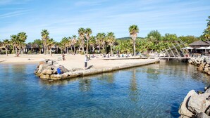 Un resort frente a la playa con palmeras, un muelle y agua cristalina.