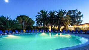 Una piscina con sillas reclinables azules y palmeras.