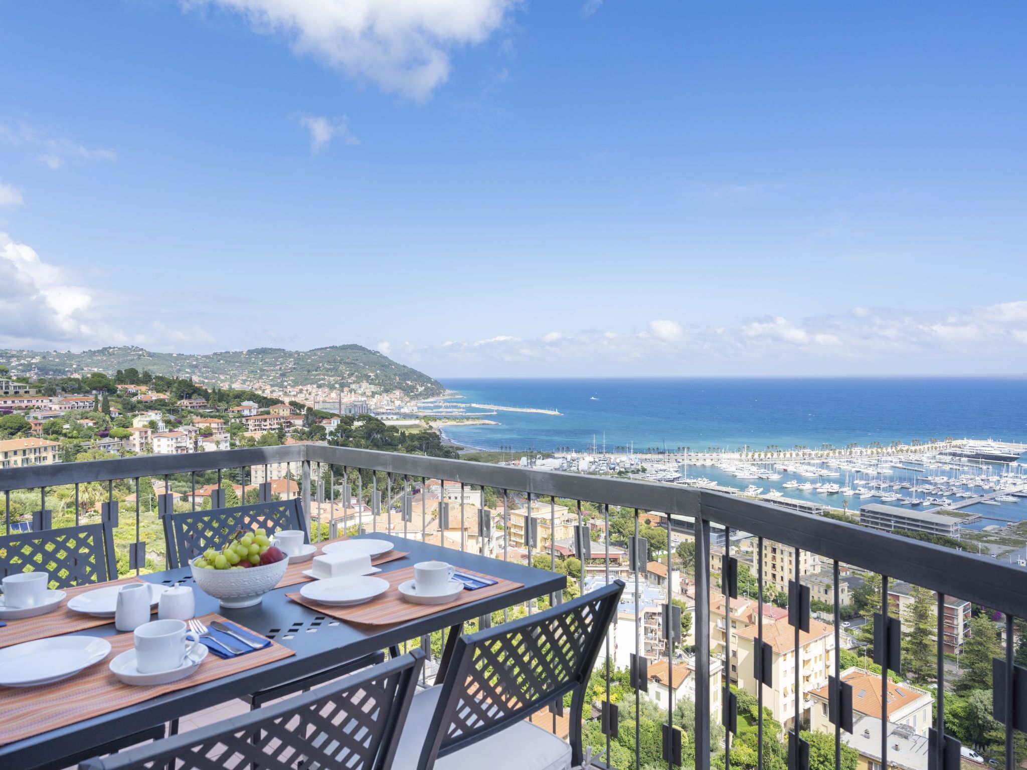 Ein Balkon mit Frühstückstisch mit Blick auf einen Yachthafen und das Meer.