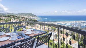 Un balcon avec une table dressée pour le petit-déjeuner, donnant sur une marina et la mer.