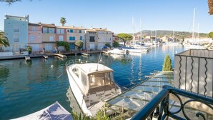 A marina with boats docked, a row of colorful buildings, and a clear blue sky. - Bleu Azur by Interhome (Port Grimaud)