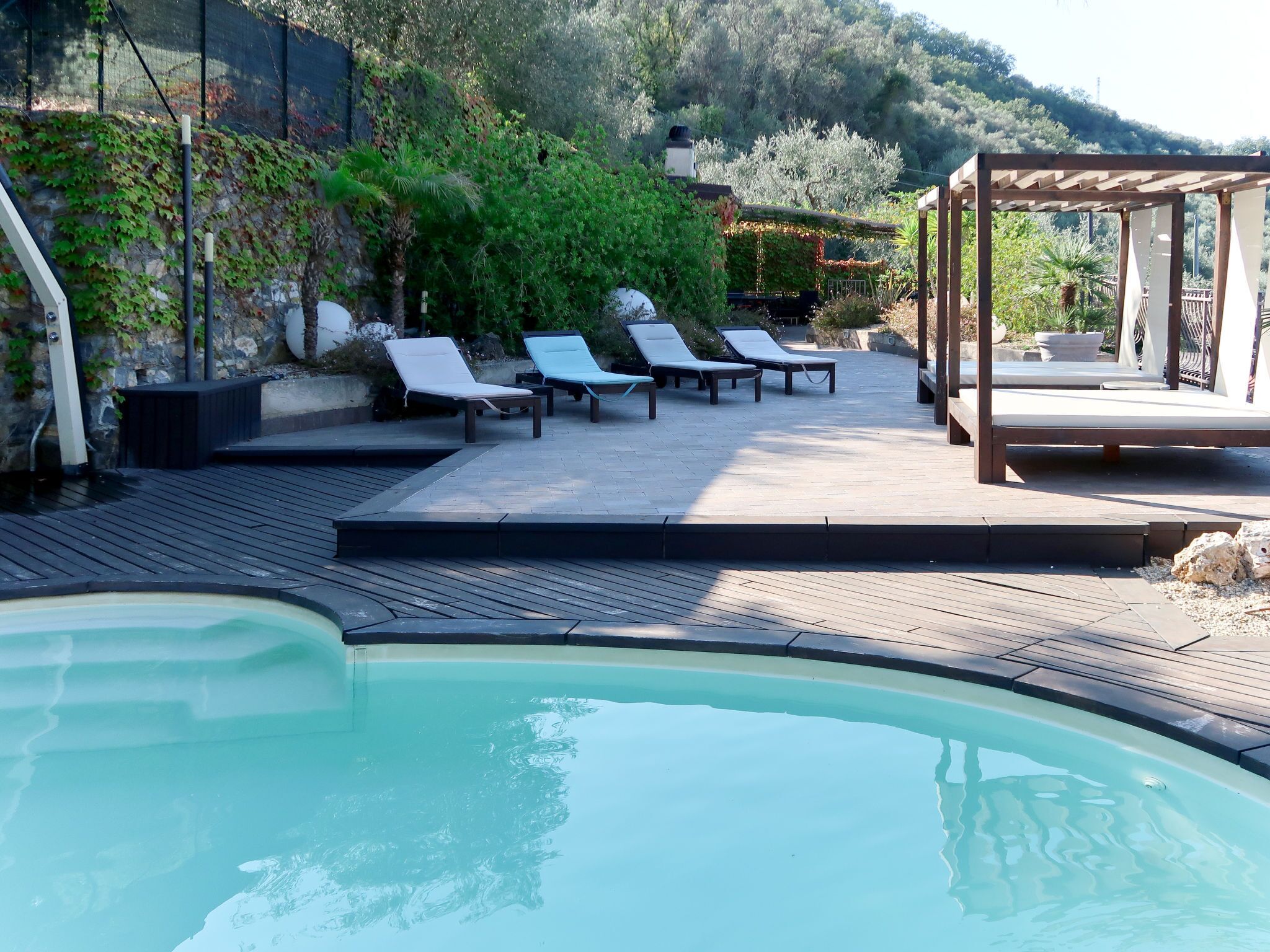 Ein Poolbereich mit Liegestühlen und einer Pergola.