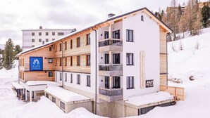 Moderni hotelli, jossa on puinen julkisivu, useita parvekkeita ja kyltti, josta ilmenee, että se kuuluu Alps Resorts -hotelliketjuun.