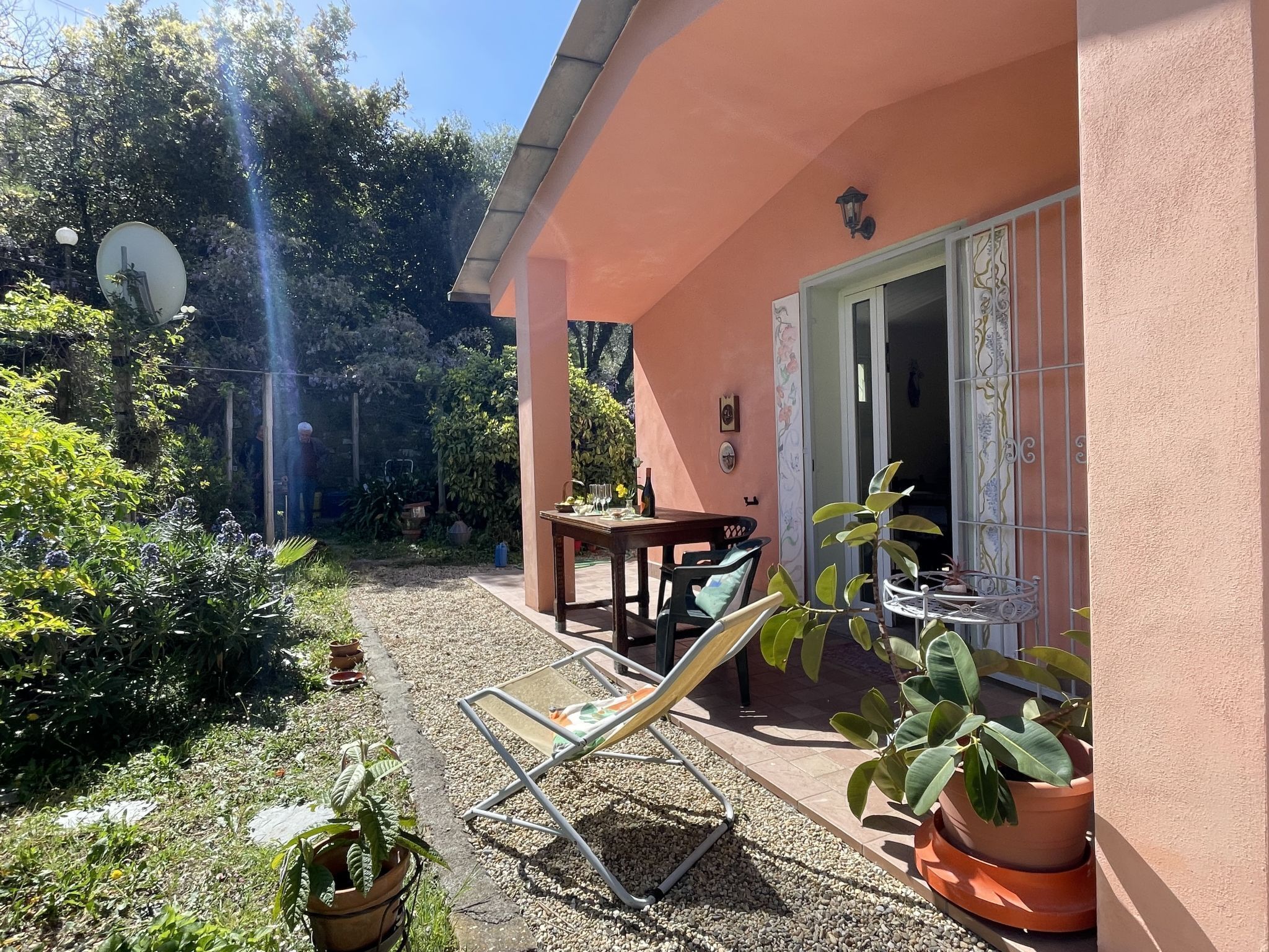 A patio with a table and chairs, surrounded by potted plants and a garden.