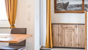 A room with a wooden cabinet, a framed photograph on the wall, and a window with curtains. - für 4 Personen by Interhome (Turracher Höhe)