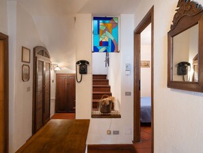 Un corridoio con una panca di legno, una scala, un telefono fissato al muro e un quadro incorniciato.
