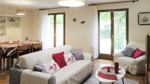 Una sala de estar con un sofá, sillones, una mesa de comedor y una zona de cocina.