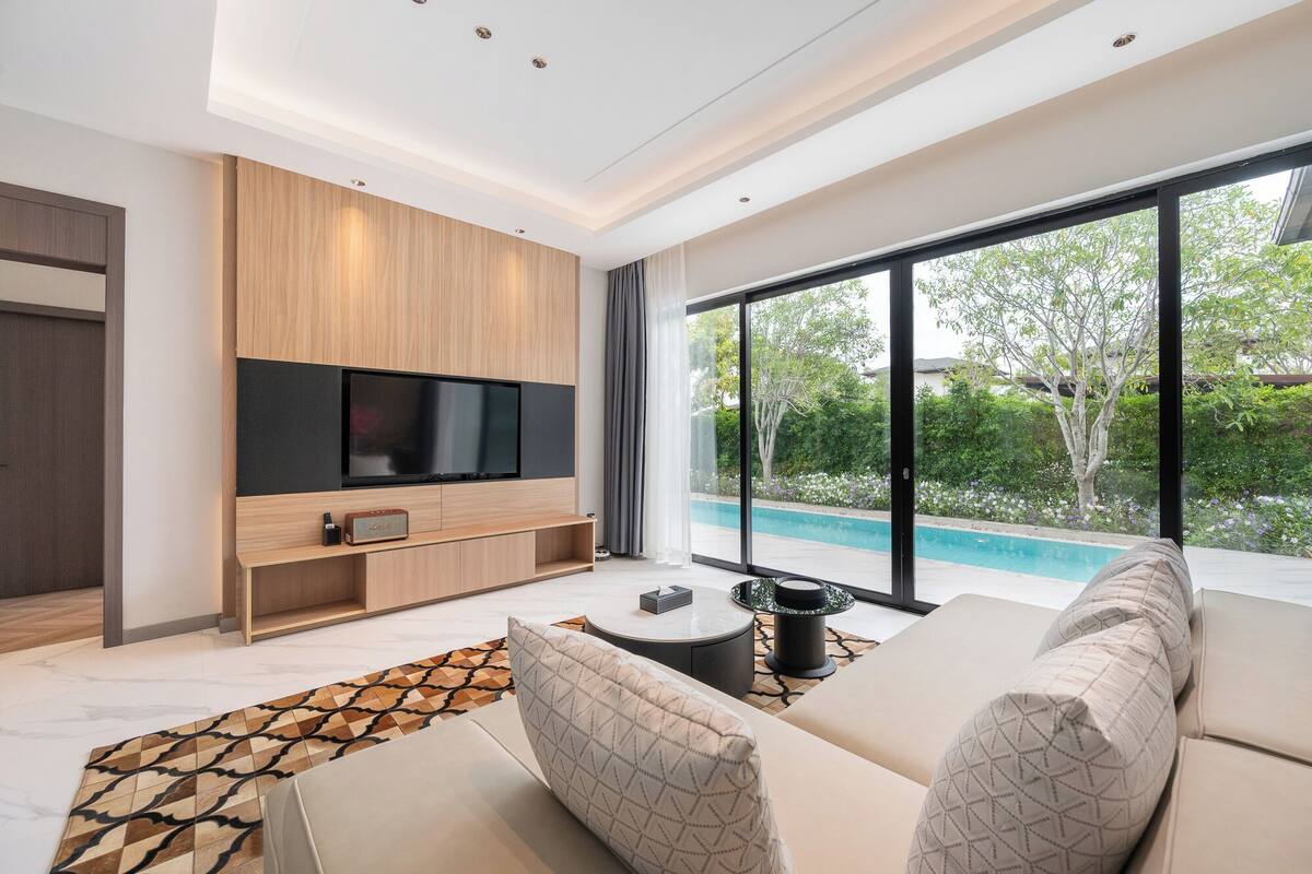Una sala moderna con un televisor grande, vistas a una piscina y una zona de estar acogedora.