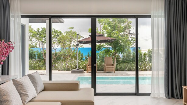 Una sala de estar moderna con un amplio ventanal corredera que da a una zona de piscina.