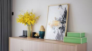 Une pièce au décor minimaliste, avec une armoire en bois, un tableau abstrait encadré, un vase de fleurs jaunes et une boîte verte.