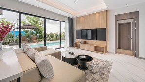 Una sala de estar moderna con un televisor grande, asientos cómodos y vista a una piscina.