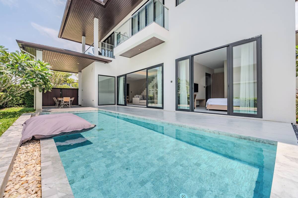 Una casa moderna con piscina, grandes puertas correderas de vidrio y un patio.