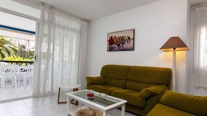 A living room with a sofa, a coffee table, and a dining area with chairs and a table. - Golf Royal Delta by Interhome (Pals)