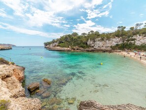 A coastal beach with clear turquoise waters, rocky cliffs, and a sandy shore. - Ca Na Rosa by Interhome (Llombards/C.Llombards/C.S'Almonia)