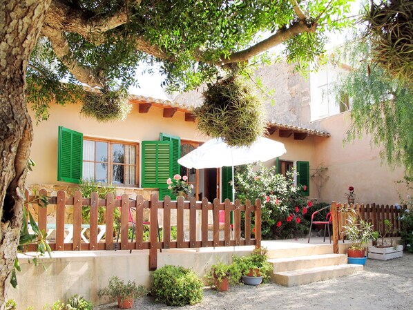 A courtyard with a wooden fence, potted plants, and a red chair.