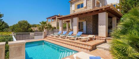 A poolside area with lounge chairs and a stone building.