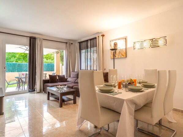 A dining area with a table set for four, a sofa, and a view of a garden.