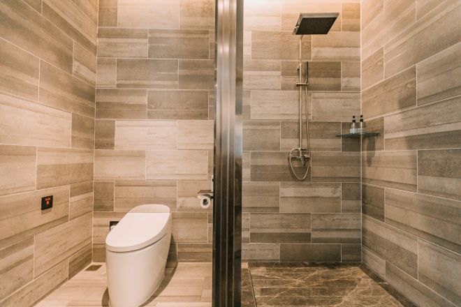 Un baño moderno con inodoro, ducha y paredes con azulejos.