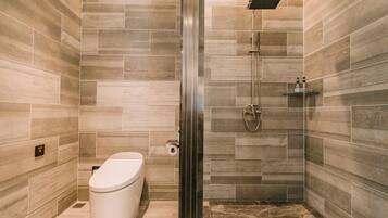 Un baño moderno con inodoro, ducha y paredes con azulejos.