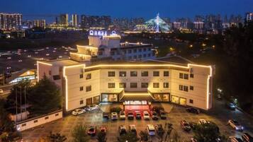 A hotel with a parking lot, a prominent tower, and a city skyline in the background.