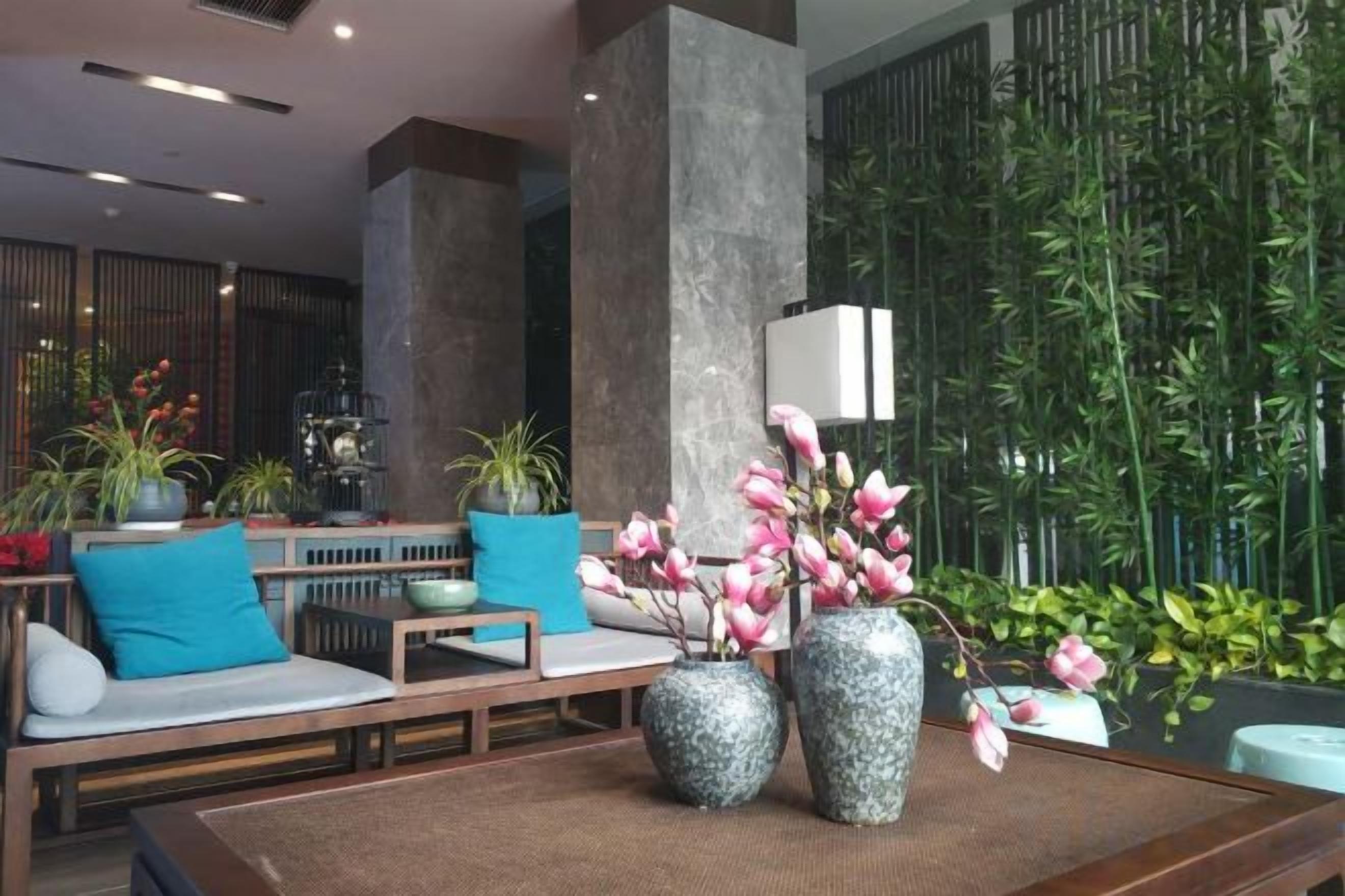 A lobby with seating, large vases, and a bamboo backdrop.