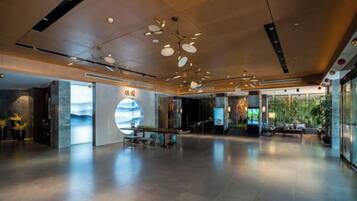 Un lobby espacioso con diseño moderno, que incluye una amplia zona de estar, una recepción y una pantalla digital.