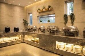 A buffet setup with various food containers and a marble counter. - Yi Yuan Hotel (Wuxi)